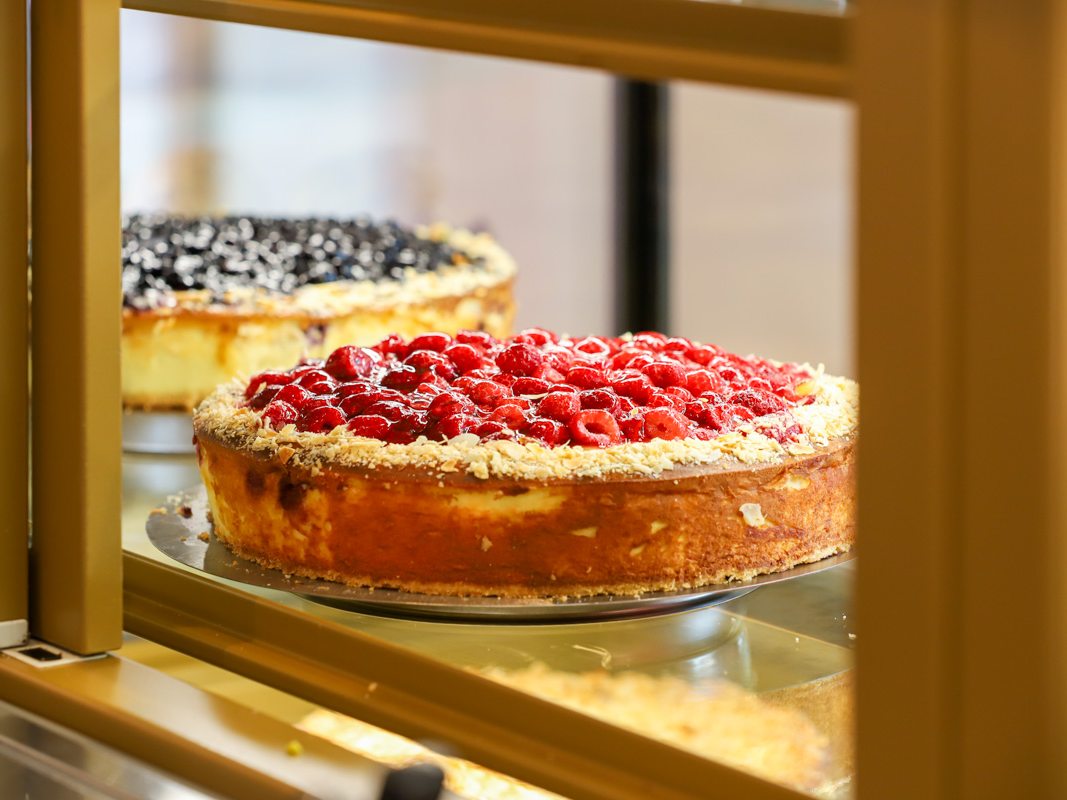 Blick in die Kuchenauslage mit Himbeer-Käsekuchen und Heidelbeerkuchen