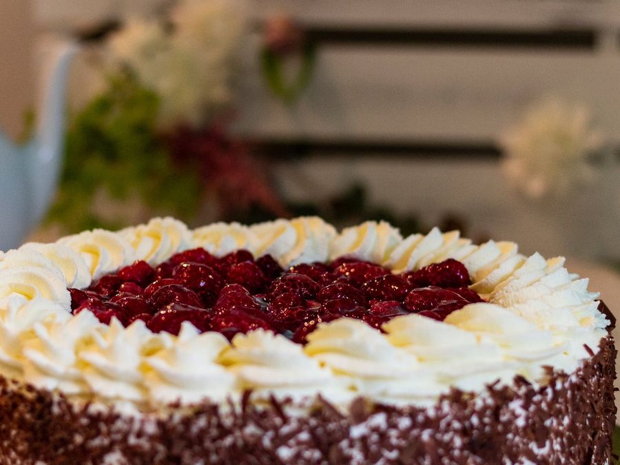 Himbeer-Schoko-Sahnetorte mit Sahnetupfen und Himbeeren obenauf