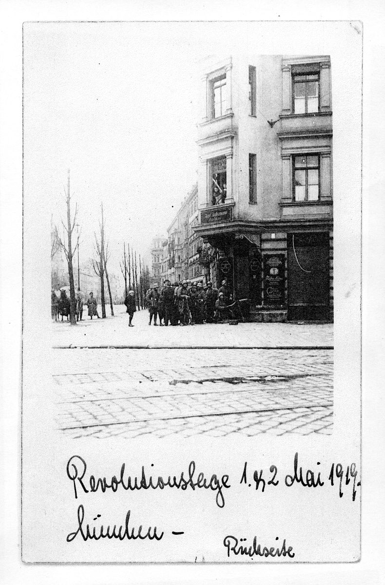 Bewaffnete Soldaten vor dem Eckhaus in der Lindwurmstraße, kahle Bäume, Menschen auf der Straße